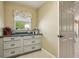 Functional laundry room with custom cabinetry, a granite countertop and a window at 1304 Zombar Pl, The Villages, FL 32163