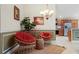 Cozy sitting area with two papasan chairs, rug, wall art, green wainscoting, plants, and view of kitchen at 1304 Zombar Pl, The Villages, FL 32163