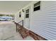 View of the front door with brick steps, black railing, and white siding at 152 Dogwood Trl, Leesburg, FL 34748