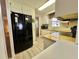 Galley kitchen featuring wood-look flooring, bright yellow countertops, white cabinets, and a black refrigerator at 152 Dogwood Trl, Leesburg, FL 34748
