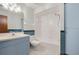 Bright bathroom features a combination tub and shower, blue cabinets, large mirror, and modern toilet at 15935 J And J Dr, Tavares, FL 32778