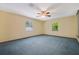 Large bedroom with blue carpet, neutral walls, ceiling fan, and natural light from two windows at 15935 J And J Dr, Tavares, FL 32778