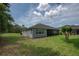 Backyard view featuring a covered lanai, lush green grass, and mature trees at 179 Birchmont Dr, Deland, FL 32724