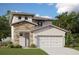 Two story home showcases a stone accent entry, light stucco siding, and a two car garage at 2048 Asher Ave, Minneola, FL 34715