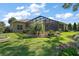 Well-manicured backyard with lush green grass, a screened-in patio, and meticulous landscaping around the home at 2204 Baypoint Way, The Villages, FL 32162