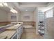 Elegant bathroom featuring double sinks, granite counters, soaking tub, stylish lighting, and a glass block shower at 2204 Baypoint Way, The Villages, FL 32162