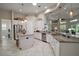 Bright kitchen with white cabinetry, granite counters, stainless appliances, island and pass-through to living space at 2204 Baypoint Way, The Villages, FL 32162