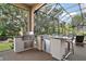 This is a screened-in outdoor kitchen featuring a stainless steel grill and mini fridge with bar seating and an outdoor view at 2204 Baypoint Way, The Villages, FL 32162