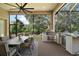 This screened lanai features a built-in outdoor kitchen and a dining area with a beautiful view of the lush backyard at 2204 Baypoint Way, The Villages, FL 32162