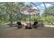 This screened patio has lounge chairs and a jacuzzi providing an inviting outdoor space with views of lush landscaping at 2204 Baypoint Way, The Villages, FL 32162