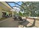 Relax in this screened patio with ample seating, an umbrella, and a jacuzzi with a beautiful view of the lush backyard at 2204 Baypoint Way, The Villages, FL 32162