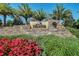 Community entrance featuring a stone sign, vibrant flowers, and lush landscaping, creating a welcoming first impression at 2602 Stargrass Cir, Clermont, FL 34715