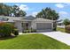 Attached garage and concrete driveway nestled in beautiful landscaping at 26030 Newcombe Cir, Leesburg, FL 34748
