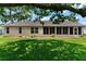Backyard view showcasing the lawn, landscaping and screened in lanai at 26608 Racquet Cir, Leesburg, FL 34748