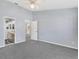 A spacious bedroom with grey carpet, ceiling fan and walk-in access to bathroom at 26608 Racquet Cir, Leesburg, FL 34748