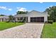 Charming single-story home featuring a brick-paved driveway, manicured lawn, and a two-car garage at 26608 Racquet Cir, Leesburg, FL 34748