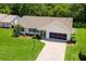 Aerial view of home featuring brick paved driveway, lush lawn, garage, and beautiful landscaping at 26608 Racquet Cir, Leesburg, FL 34748