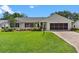 This cozy single-story home features a screened garage, brick-paved driveway, and manicured lawn at 26608 Racquet Cir, Leesburg, FL 34748