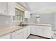 Well-lit kitchen area with white cabinetry, stainless steel sink, and dishwasher at 26608 Racquet Cir, Leesburg, FL 34748