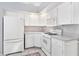 Efficient kitchen featuring white cabinets and appliances, enhanced by tile flooring at 26608 Racquet Cir, Leesburg, FL 34748