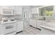 Functional kitchen design featuring white appliances, tile floors and view to lanai at 26608 Racquet Cir, Leesburg, FL 34748