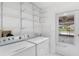 Bright laundry room with white washer, dryer, storage shelves, sink, and exterior door at 26608 Racquet Cir, Leesburg, FL 34748
