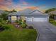 Charming single-story home featuring a three-car garage, a well-kept lawn and colorful landscaping at 3136 Vandenberg Ct, The Villages, FL 32163