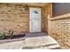 Close up of front door with white trim and brick accent with greenery at 3380 Blossom St, Kissimmee, FL 34746