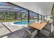 Covered patio with a dining table and chairs overlooking a screened-in pool and landscaped backyard at 3380 Blossom St, Kissimmee, FL 34746