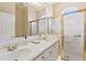 Bright bathroom featuring double sinks, a mirrored wall, and a glass-enclosed shower at 34021 Park Ln, Leesburg, FL 34788
