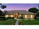 Charming exterior view of a single-story home with a red front door and well-manicured landscaping at 34021 Park Ln, Leesburg, FL 34788