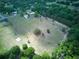 Aerial shot of a vast lot with scattered trees and buildings surrounded by lush greenery and neighboring homes at 37149 Grays Airport, Lady Lake, FL 32159