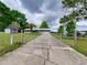 Wide driveway with gate, mature trees, and shed in the background at 37149 Grays Airport, Lady Lake, FL 32159