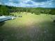 Vast, grassy lot with scattered trees and parked vehicles, under a partly cloudy sky, suitable for development at 37149 Grays Airport, Lady Lake, FL 32159
