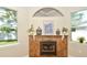 Close-up of a stone fireplace with decorative items, windows providing natural light, and neutral paint colors at 3732 Fallscrest Cir, Clermont, FL 34711