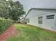 Green backyard with mulched garden beds, a privacy hedge, and the side of the home at 3821 Doune Way, Clermont, FL 34711
