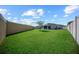 Expansive backyard with a well-maintained lawn, bordered by a privacy fence, and featuring a young tree at 4451 Elijah Loop, The Villages, FL 32163