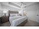 Bright main bedroom features a tray ceiling, ceiling fan and large windows at 4451 Elijah Loop, The Villages, FL 32163