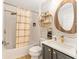 Stylish bathroom features tile surround, gold fixtures, floating shelves, and a decorative mirror for a modern aesthetic at 467 Weston Manor Dr, The Villages, FL 32162