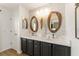 This is a bathroom with dual sinks, unique mirrors, and modern fixtures at 467 Weston Manor Dr, The Villages, FL 32162