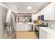 Modern kitchen with stainless steel appliances, white cabinets, breakfast bar, and an open view to the living area at 467 Weston Manor Dr, The Villages, FL 32162