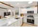 Bright kitchen boasts white cabinets, stainless steel appliances, a breakfast bar, and modern backsplash at 467 Weston Manor Dr, The Villages, FL 32162
