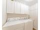 Functional laundry room features modern appliances, ample storage cabinets, and a convenient sink area at 467 Weston Manor Dr, The Villages, FL 32162