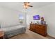 Bedroom features natural light, a ceiling fan, and wooden dresser with mounted TV at 4869 Grassendale Ter, Sanford, FL 32771