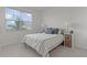 Bright bedroom with a large window, a comfortable bed with striped bedding, and white nightstands at 5043 Stokes Way, Wildwood, FL 34785