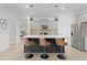 Modern kitchen featuring a black island with a granite countertop, stainless steel appliances, and three bar stools at 5043 Stokes Way, Wildwood, FL 34785