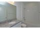 Bathroom with a granite vanity top, large mirror, and a shower-tub combo with white tiles at 5045 Balsam Falls Rd, Deland, FL 32724