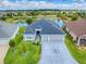 Stunning aerial view of home with pond, manicured lawn, and three-car garage in a well-maintained community at 5905 Caulk Ct, The Villages, FL 32163