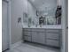 Well lit main bathroom featuring double vanity with gray cabinets, and open decorative shelving at 5905 Caulk Ct, The Villages, FL 32163