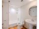Bright bathroom featuring a tiled shower-tub combination, and a pedestal sink with a round mirror at 601 W Old Hwy 441 # 11B, Mount Dora, FL 32757